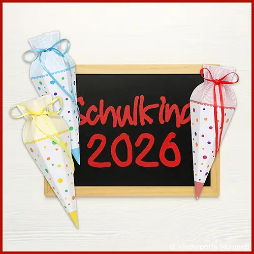 Drei kleine Schultüten mit bunten Punkten und Schleifen in Gelb, Blau und Rot neben einer Tafel mit roter Schrift 'Schulkind 2026'