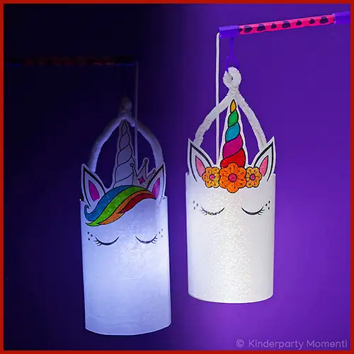 Zwei selbstgebastelte Einhornlaternen an Laternenstäben vor einem Lila Hintergrund