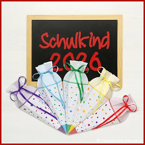 Fünf kleine Schultüten mit bunten Punkten und farbigen Schleifen vor einer Tafel mit roter Schrift 'Schulkind 2026'