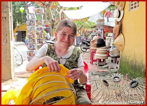 Laternenbau in Vietnam Frau sitzt im Vietnam-Urlaub an einer Straße und beklebt Laternenlampe