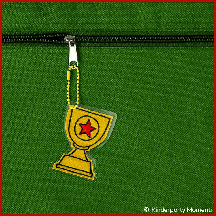 Fußballpokal Anhänger als DIY Reflektor Anhänger in Form eines Pokals mit rotem Stern an einer grünen Tasche befestigt