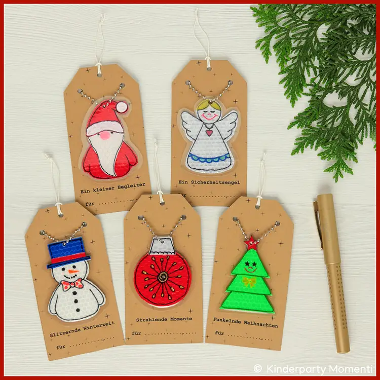 Weihnachtliche Geschenkanhänger aus reflektierender Klebefolie Fünf braune Geschenkanhänger mit reflektierenden Weihnachtsmotiven: Weihnachtsmann, Engel, Schneemann, Christbaumkugel und Weihnachtsbaum, jeweils mit Kugelkette.