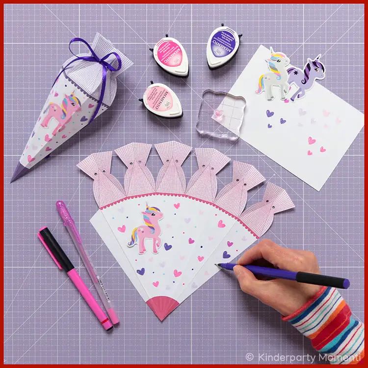 Kleine Schultüte bemalen und bestempeln Eine Hand bemalt eine kleine Schultüte, um die Schultüten Vorlage herum liegen Bastelwerkzeuge.