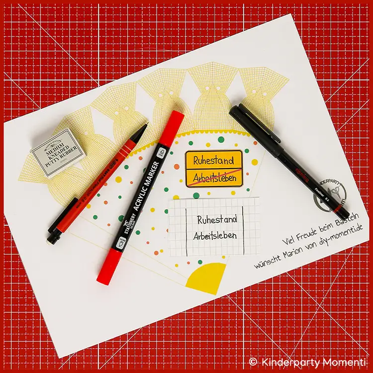 Mini Schultüte mit persönlichem Meilenstein beschriften Bastelvorlage für eine Mini-Schultüte mit handschriftlichen Beschriftungen und drei Stiften auf roter Bastelmatte