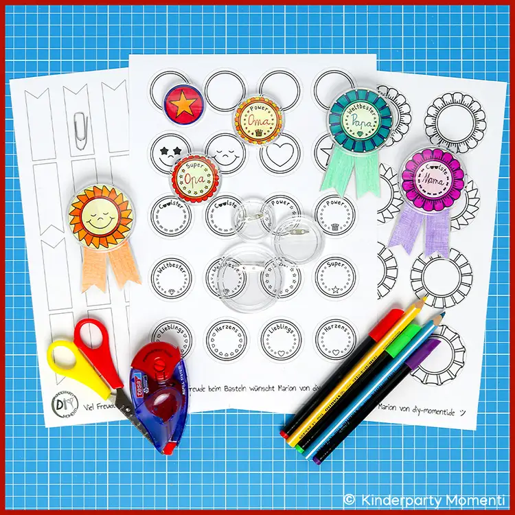 Bastelmaterial und Vorlagen für DIY Orden aus Klick Button Bastelbögen mit runden Orden zum Ausschneiden und Ausmalen, Schere, Kleberoller und bunte Filzstifte auf blauem Schneideunterlage